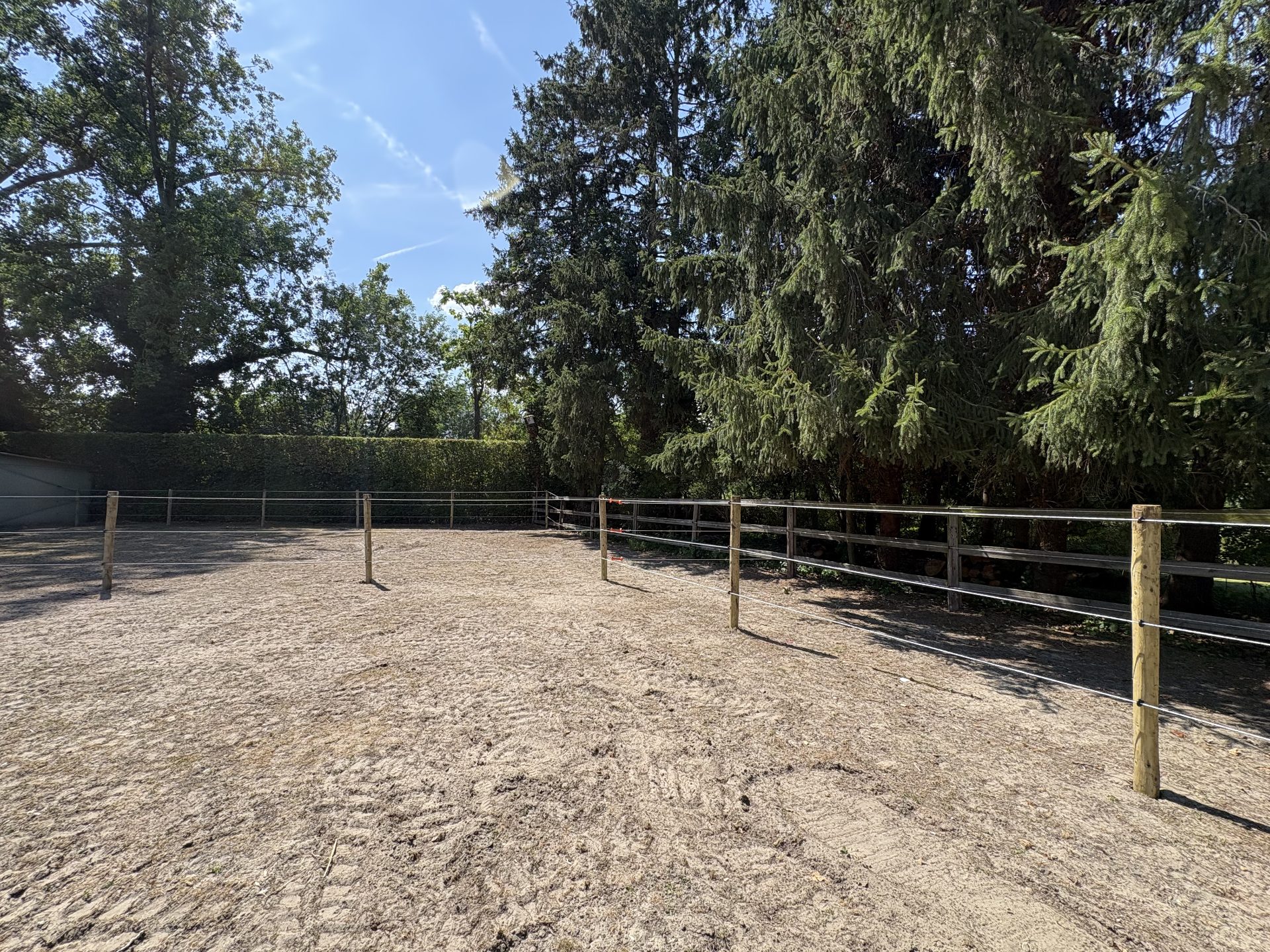 Electric fencing around a sand paddock with a wooden perimeter fence
