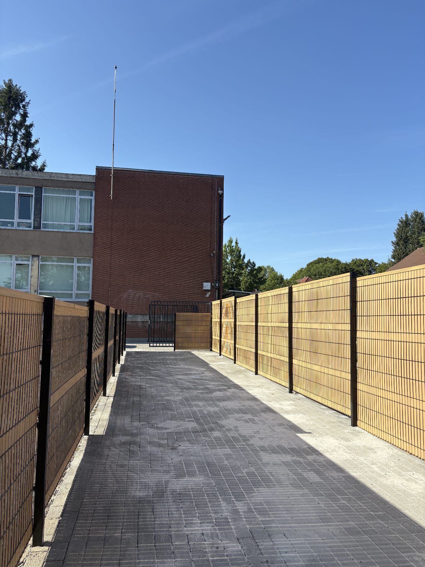 Steel and wood privacy fencing with gate at a school building